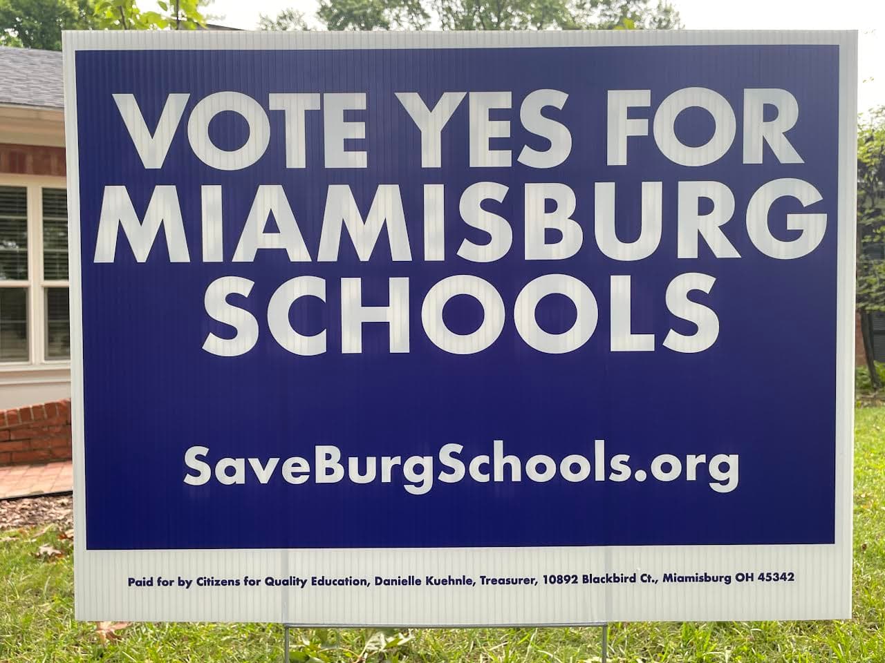 Blue yard sign reading Vote Yes for Miamisburg Schools and SaveBurgSchools.org